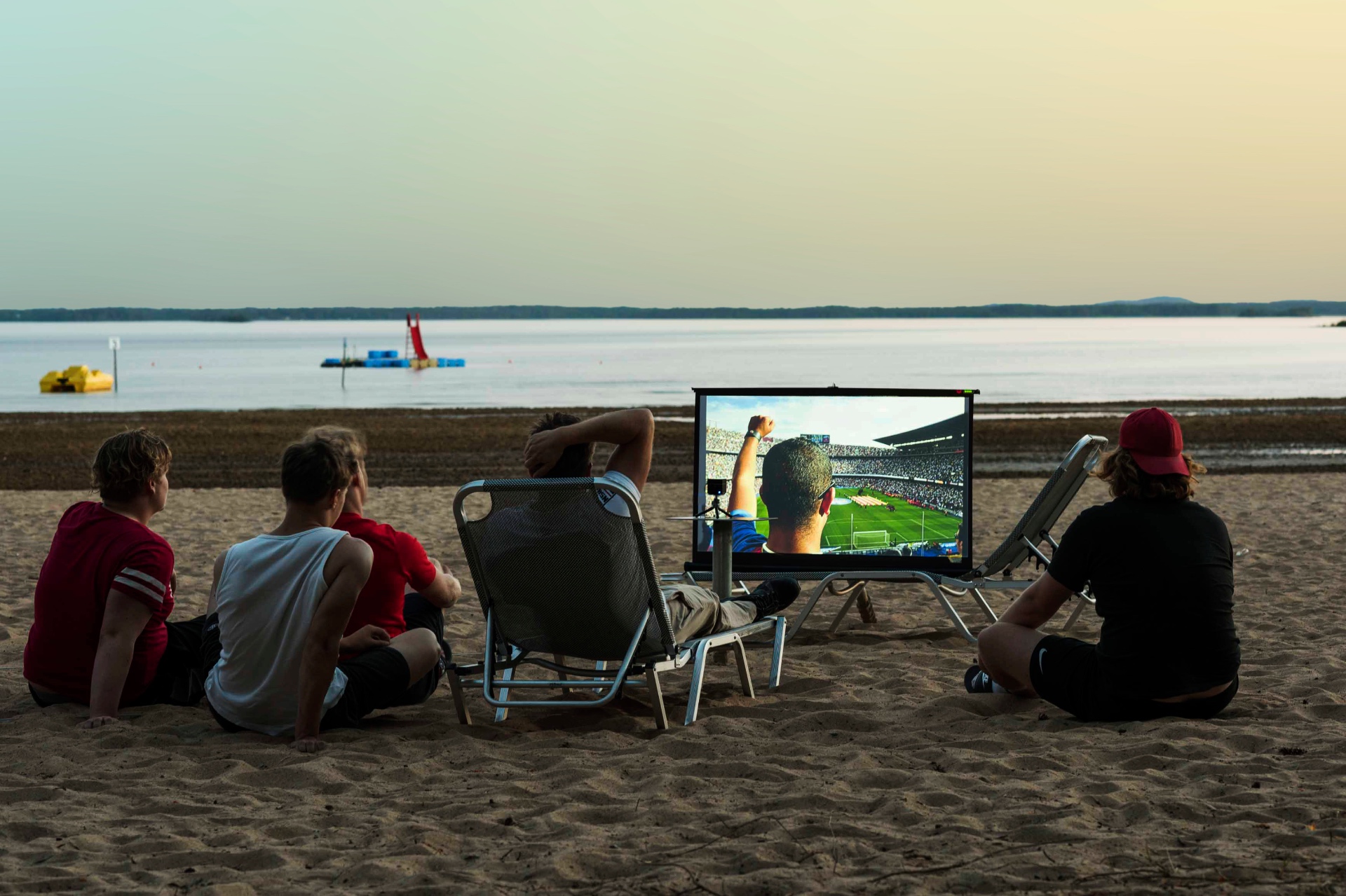 Vänner ser fotboll på duk vid stranden i skymningen med PICZO Nova Ultra S