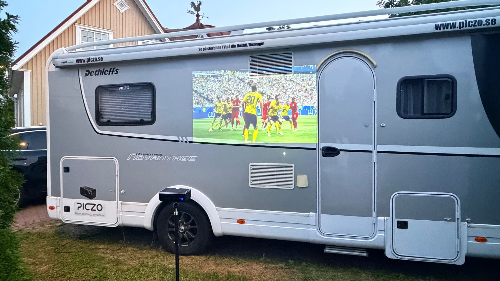 PICZO Nova Ultra S projicerar en fotbollsmatch på sidan av en husbil i sommarkvällen
