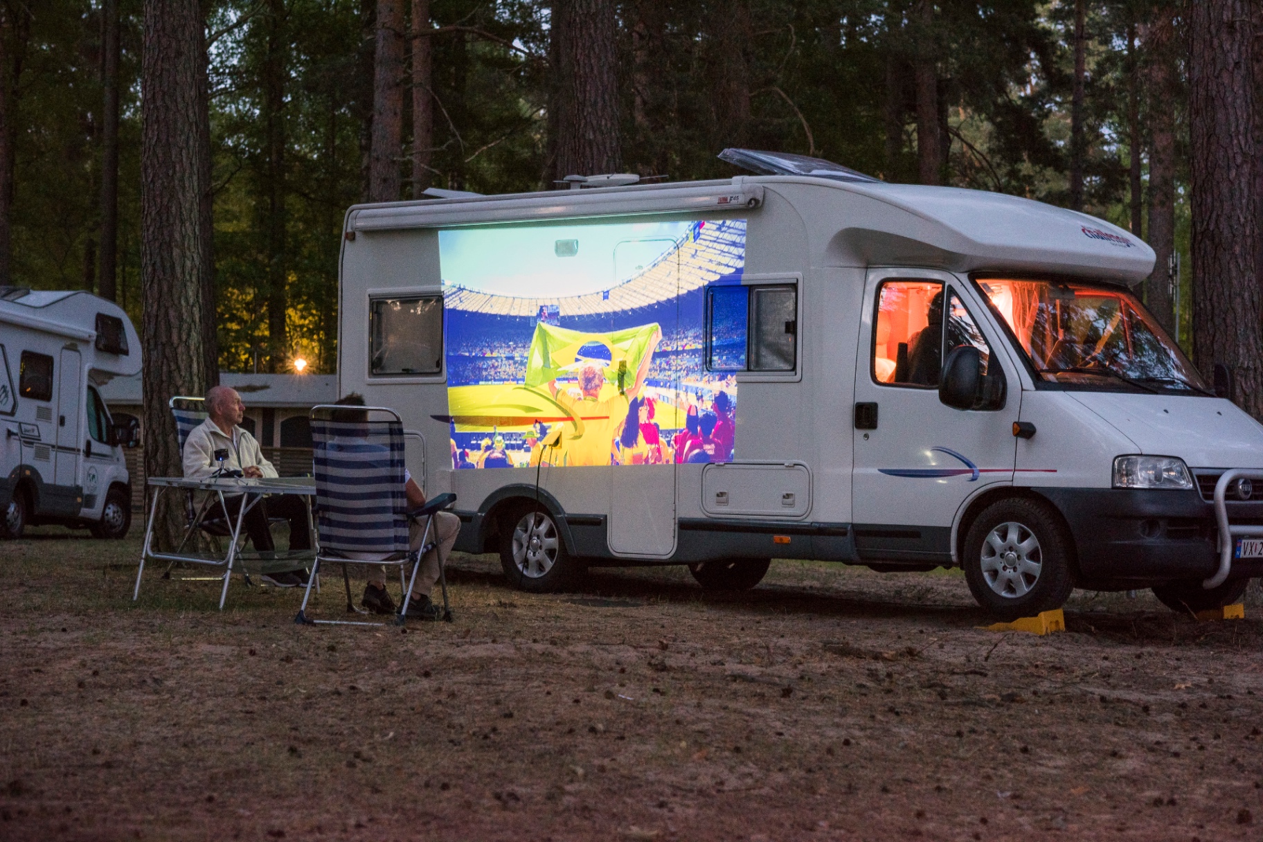 Husbil på camping med PICZO Nova Ultra S som projicerar fotboll på sidan av fordonet